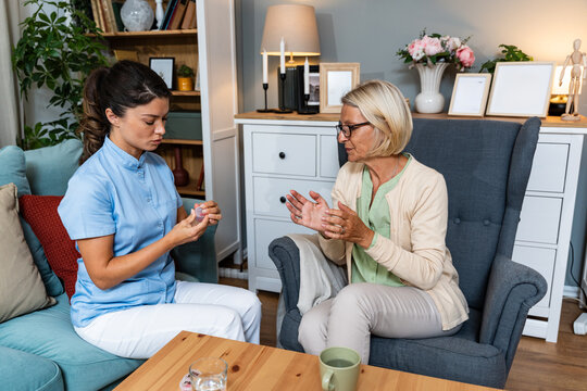Home hearing care visit: nurse explains and fits a hearing aid for an older woman, gentle coaching and device setup during an in-home audiology consultation to improve communication and daily life
