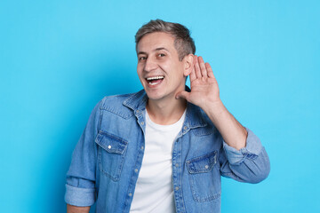 Man showing hand to ear gesture on light blue background