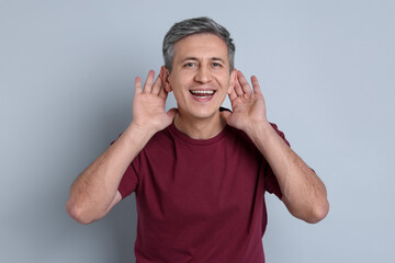 Naklejka premium Man showing hand to ear gesture on light grey background