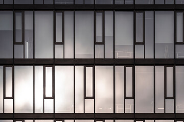 A modern facade where architecture blends geometry with minimal structure, revealing abstract detail and subtle texture in a patterned exterior captured during calm daylight with soft reflections