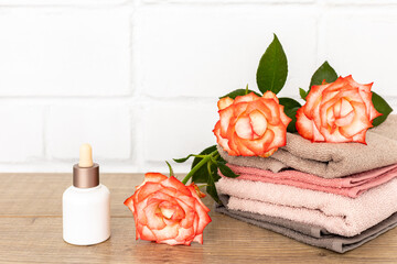 Spa composition with towels, flowers and facial serum on the wooden boards.