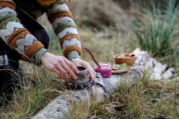 Healthy breakfast in the nature, eating home made bread and beet root pesto, drinking natural herbal tea