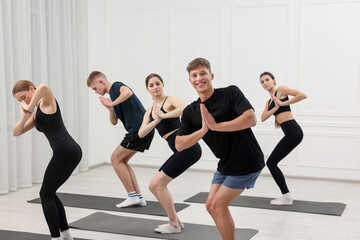 Fototapeta premium Group of people doing stretching exercise on fitness mats in gym
