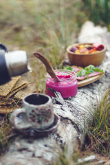 Healthy breakfast in the nature, eating home made bread and beet root pesto, drinking natural herbal tea