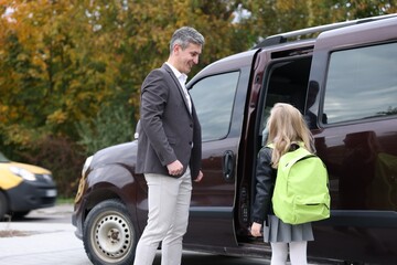 Father taking his daughter to school near car outdoors
