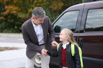 Father taking his daughter to school near car outdoors