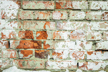 A dilapidated old red brick wall painted white as an abstract background.