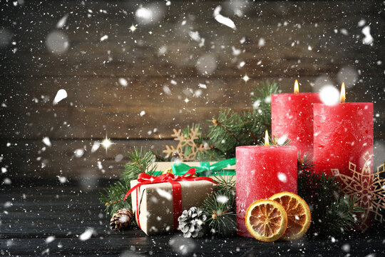 Christmas composition with candles on table under falling snow. Greeting card design
