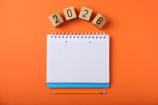 New 2026 year. Cubes with numbers, notebook and pencil on orange background, top view - Powered by Adobe