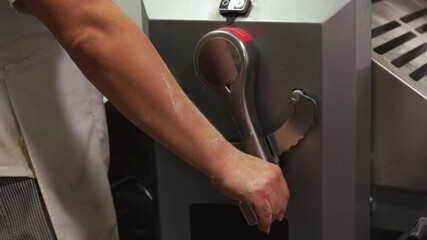 Closeup of a baker's hand using a bakery machine for laminating the integral dough for puff pastry - Powered by Adobe