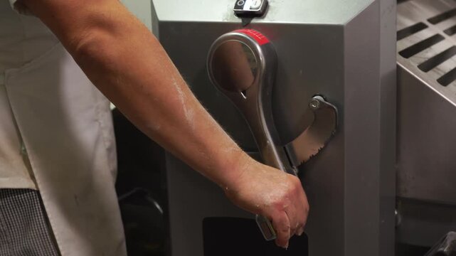 Closeup of a baker's hand using a bakery machine for laminating the integral dough for puff pastry