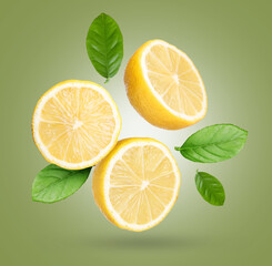 Fresh lemons and green leaves falling on olive color background. Citrus fruit
