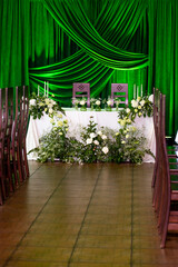 Elegant wedding ceremony setup with green drapes and floral arrangements