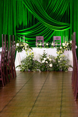 Elegant green and white wedding reception decor with floral arrangements and green drapery