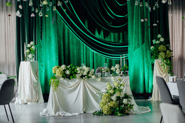 Elegant wedding reception decor with green drapes and white floral arrangements
