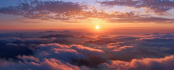 Fototapeta premium Panoramic vista shows sunrise over mountains blanketed in clouds with colorful sky above
