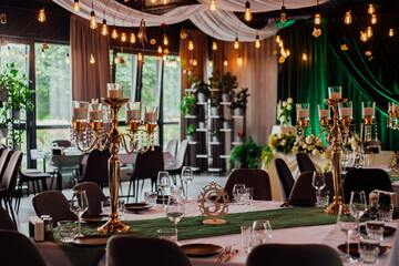 Elegant wedding reception with candleholders and green accents in decorated banquet hall