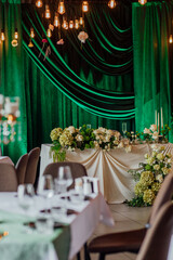 Elegant wedding reception with green drapes and floral centerpieces