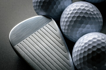 Golf iron next to golf balls in dark setting