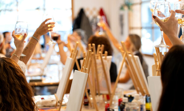 Women toasting at a creative sip and paint workshop - Powered by Adobe