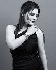 Graceful and confident woman posing in a one-shoulder black dress, captured in a monochrome studio portrait symbolizing beauty, sophistication, and inner strength.