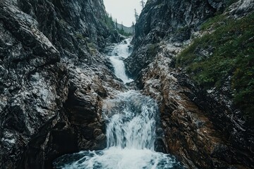 A narrow, steep, rocky chute with a rushing waterfall cascading down, representing imminent danger and a perilous descent , wild, mountain
