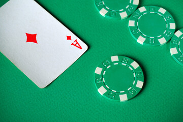 Poker chips in green and white sit beside an ace card on a vibrant green table surface, setting the stage for an exciting evening of card games with friends
