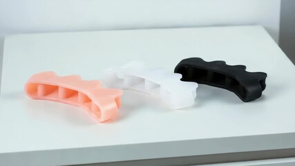 Silicone finger stretchers on a white surface promoting hand exercise and rehabilitation tools, colorful stress relief gadgets for muscle training, occupational therapy aids