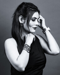 Monochrome fashion portrait of a confident woman in a black one-shoulder dress, captured in a calm and reflective side pose that conveys elegance and strength.