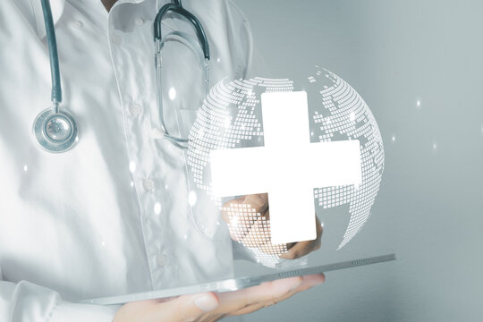 Doctor holding tablet with virtual globe and medical cross icon. Global healthcare, health insurance, and international medical service network concept.