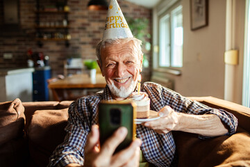 Senior man happily celebrating birthday on video call at home
