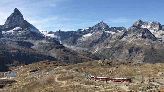 The red Gornergrat Bahn cogwheel train with the Matterhorn peak in the background, Zermatt, Switzerland.