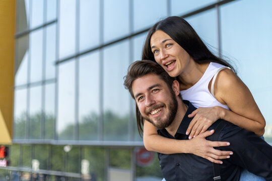 A man carrying a woman on his back through a lush forest trail,