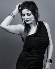Monochrome portrait of a confident woman in a black one-shoulder dress, posing gracefully with a soft expression. Perfect for fashion, beauty, and lifestyle themes representing elegance and confidence
