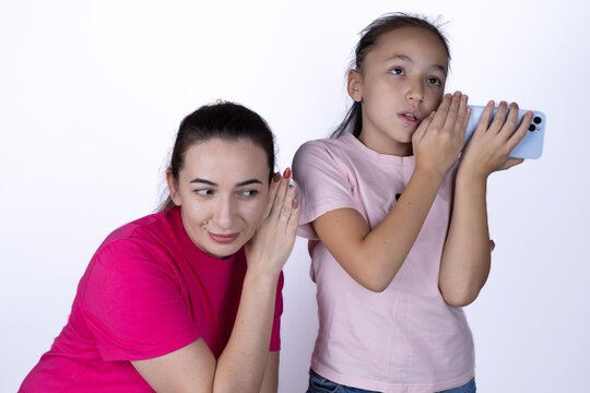  Mother and daughter are intently listening to something, one using a smartphone