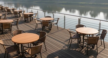 Serene waterfront restaurant patio with empty wooden tables on a sunny deck