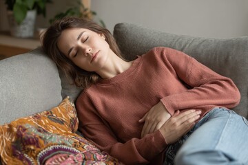 Female with abdominal pain resting on couch at home