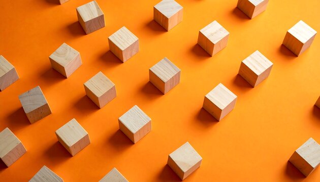 Wood cubes arranged on bright orange background, evenly spaced, creating pattern from above in sunlight