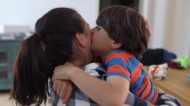 Mother and son exchanging affectionate kiss in warm embrace, expressing mutual love, trust, and tenderness during quiet family moment at home