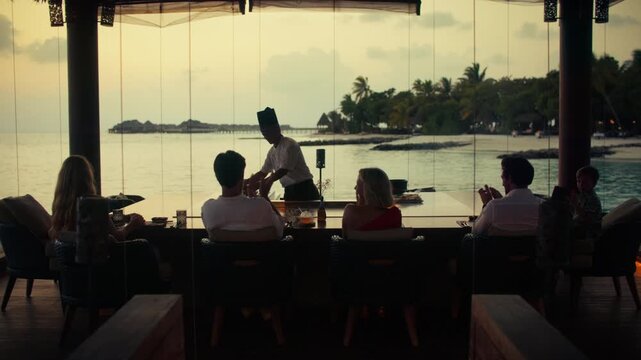 Family enjoying a luxurious culinary experience with a private chef and stunning ocean views at sunset