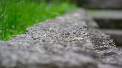 Low angle view of stone podium table top floor on outdoors grass background in bokeh.
