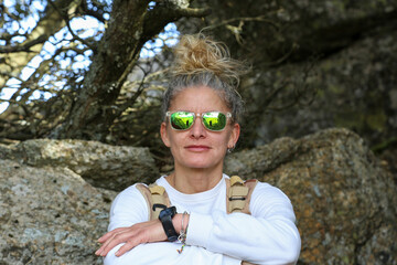 Portrait of a blonde woman with sunglasses and her hair tied in a bun in mountain