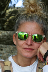 Portrait of a blonde woman with sunglasses and her hair tied in a bun in mountain