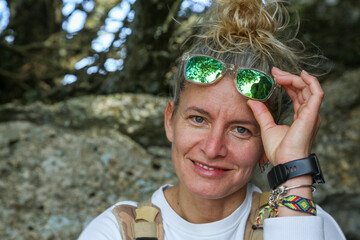 Portrait of a blonde woman with sunglasses and her hair tied in a bun in mountain