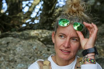 Portrait of a blonde woman with sunglasses and her hair tied in a bun in mountain