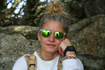 Portrait of a blonde woman with sunglasses and her hair tied in a bun in mountain