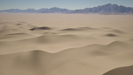 Golden sand dunes stretch endlessly, kissed by sunlight. The serene landscape features gentle waves of sand leading to majestic mountains in the background, creating a peaceful yet dramatic scene.