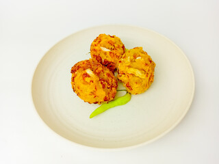 Bala-Bala or vegetable fritters with chili served on a round plate, isolated on white background.