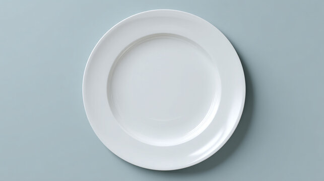 A top down view of a simple white ceramic plate centered on a light gray background surface