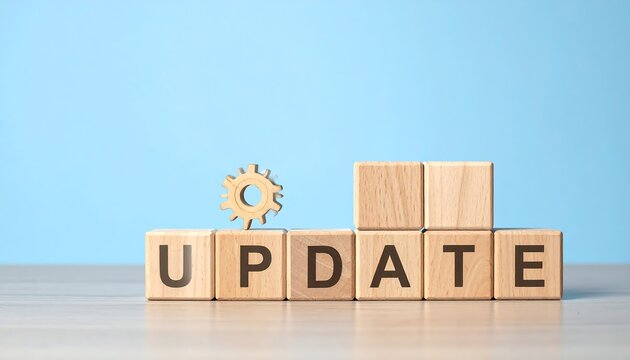 Wooden blocks spell "UPDATE," with a gear and additional blocks on a pale blue and white surface. Simple yet effective design